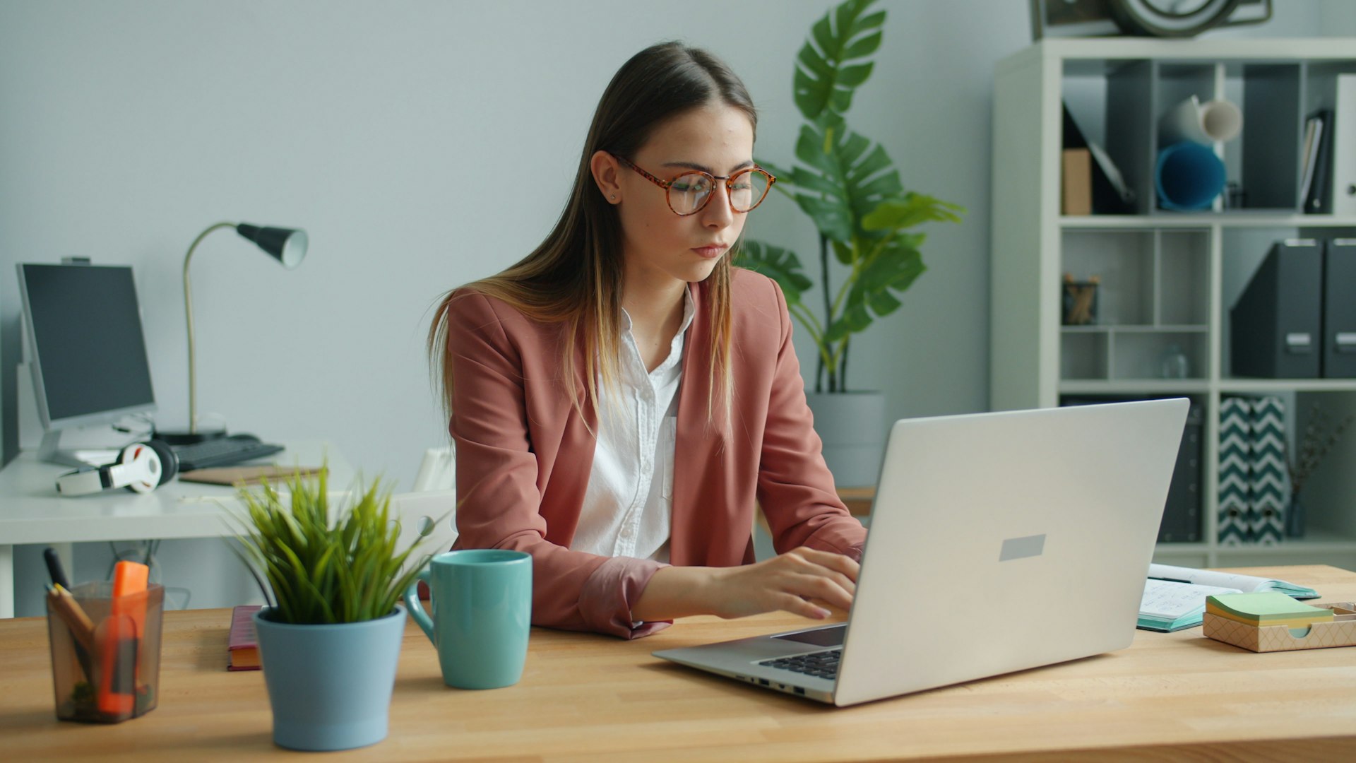 Young woman working on a laptop at a desk.