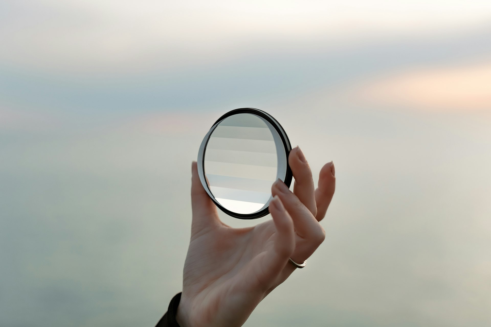 a hand holding a magnifying glass over a body of water